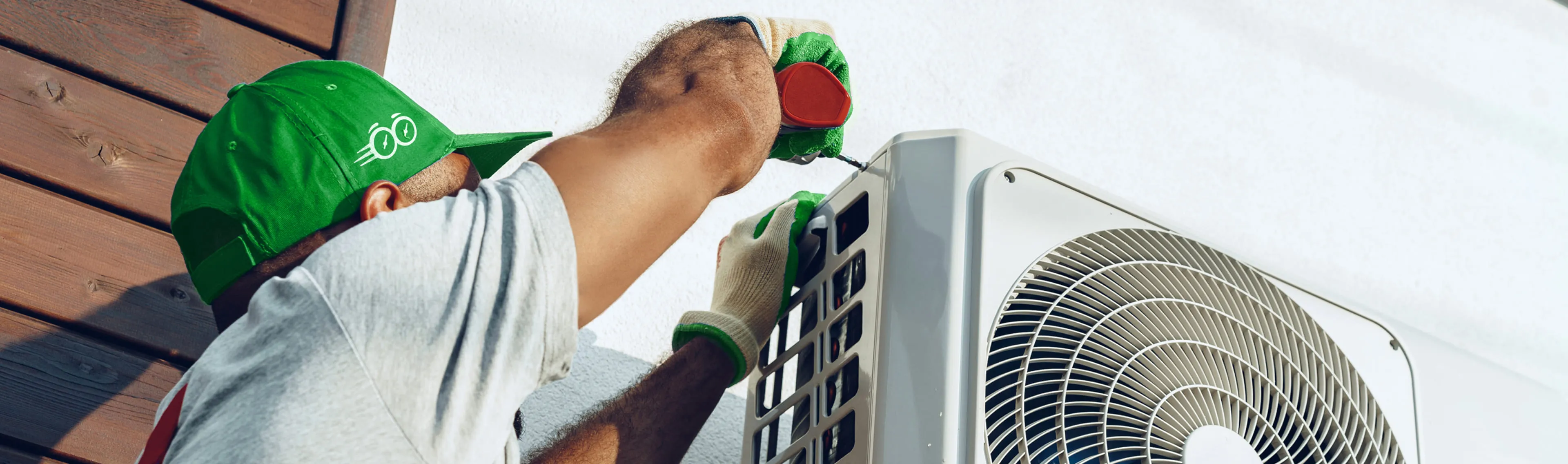 Rapid Response team member securing an outdoor AC condenser unit to the wall during installation service
