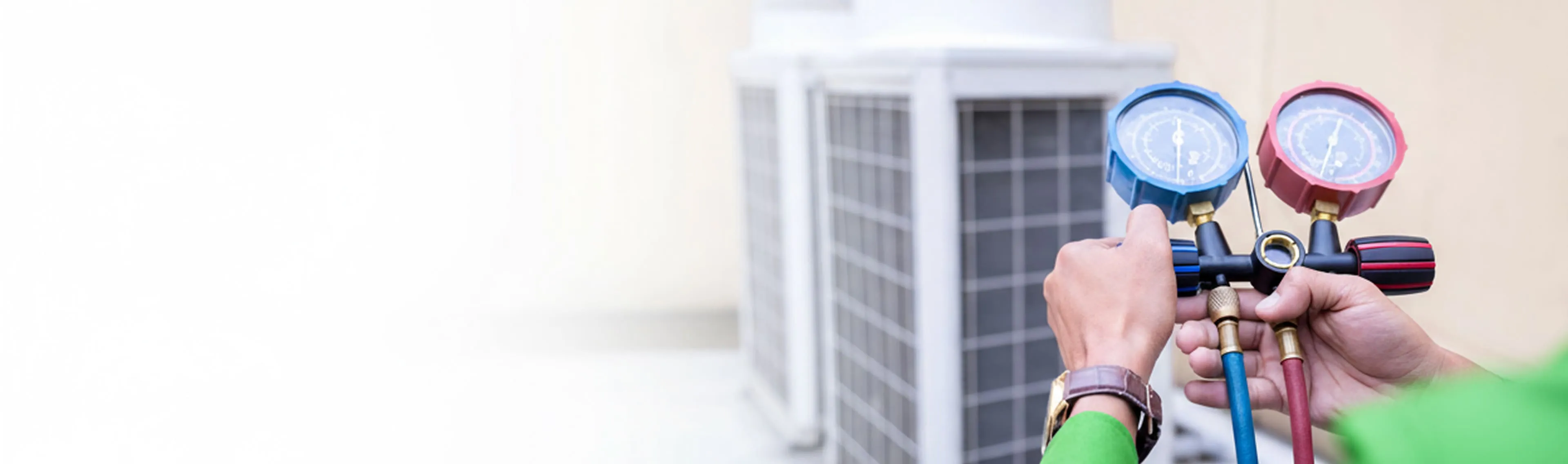 A technician is checking refrigerant pressure gauges to ensure the outdoor air conditioning unit is working efficiently