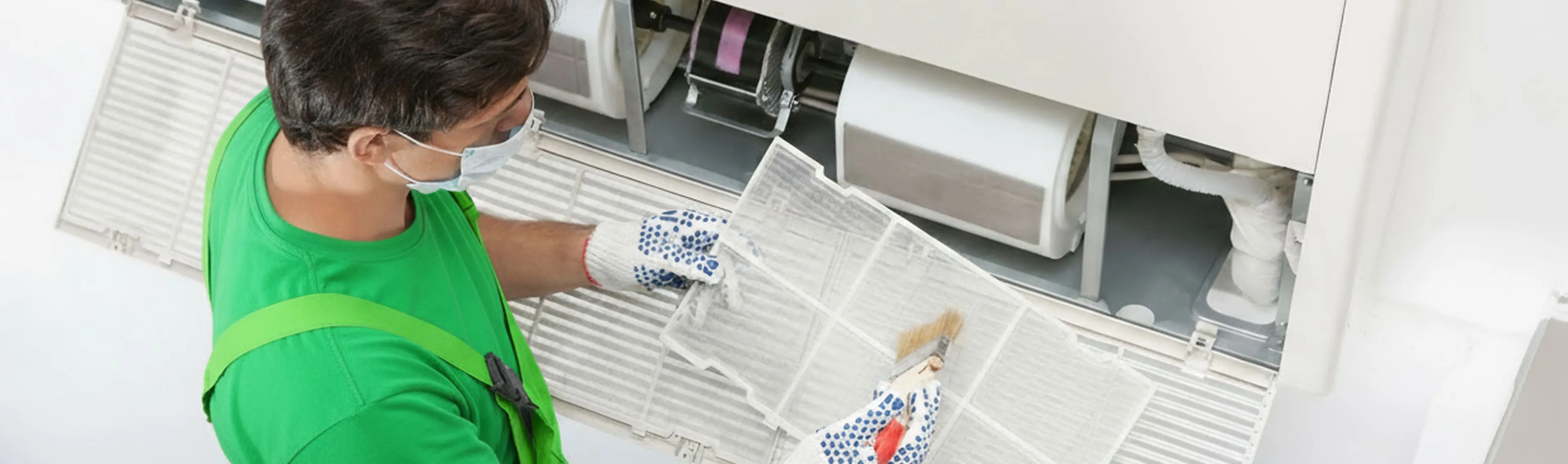 A technician is removing and brushing an AC air filter to improve airflow and indoor air quality