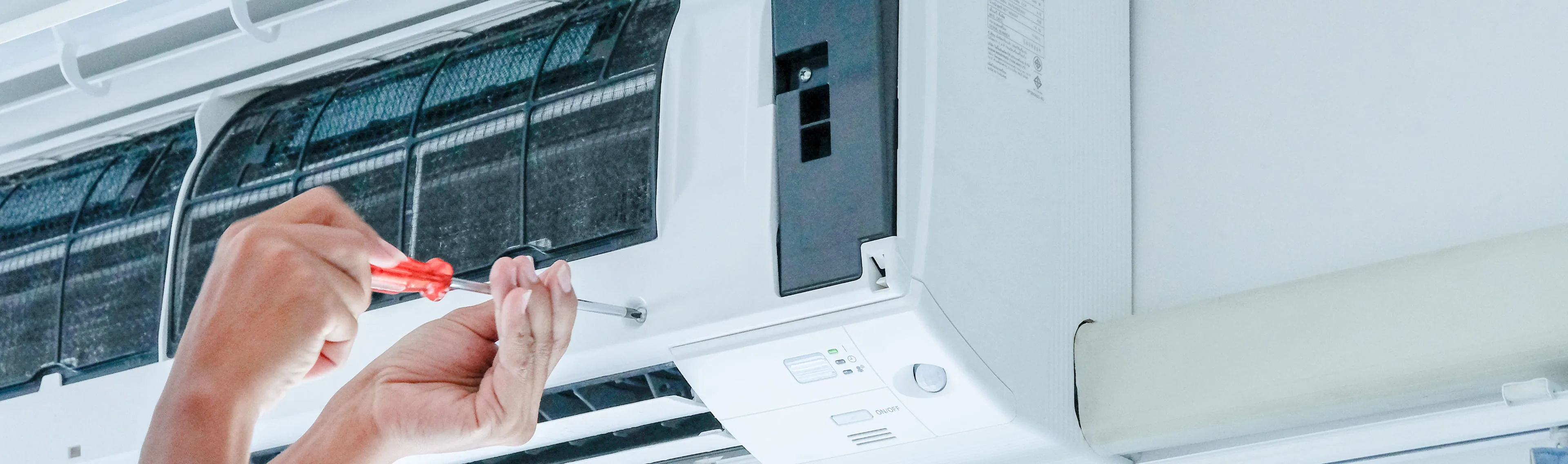 A technician uses a screwdriver to install a mini split indoor unit, aligning components for a secure and clean fit