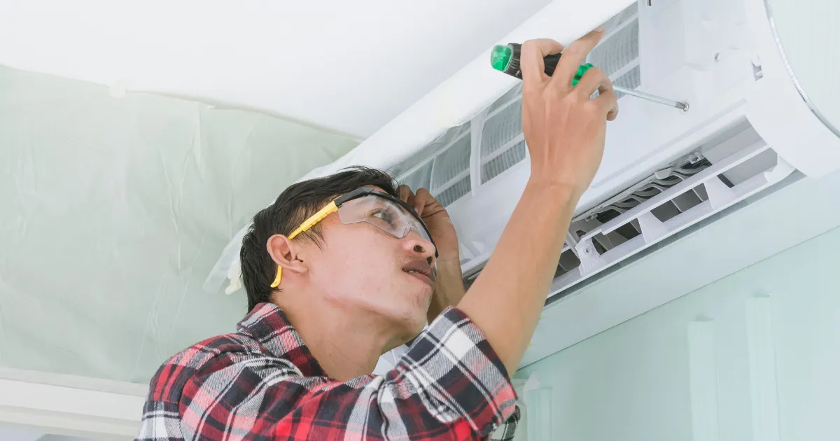 Routine AC unit maintenance is being done by a Rapid Response team member, adjusting the front panel with care