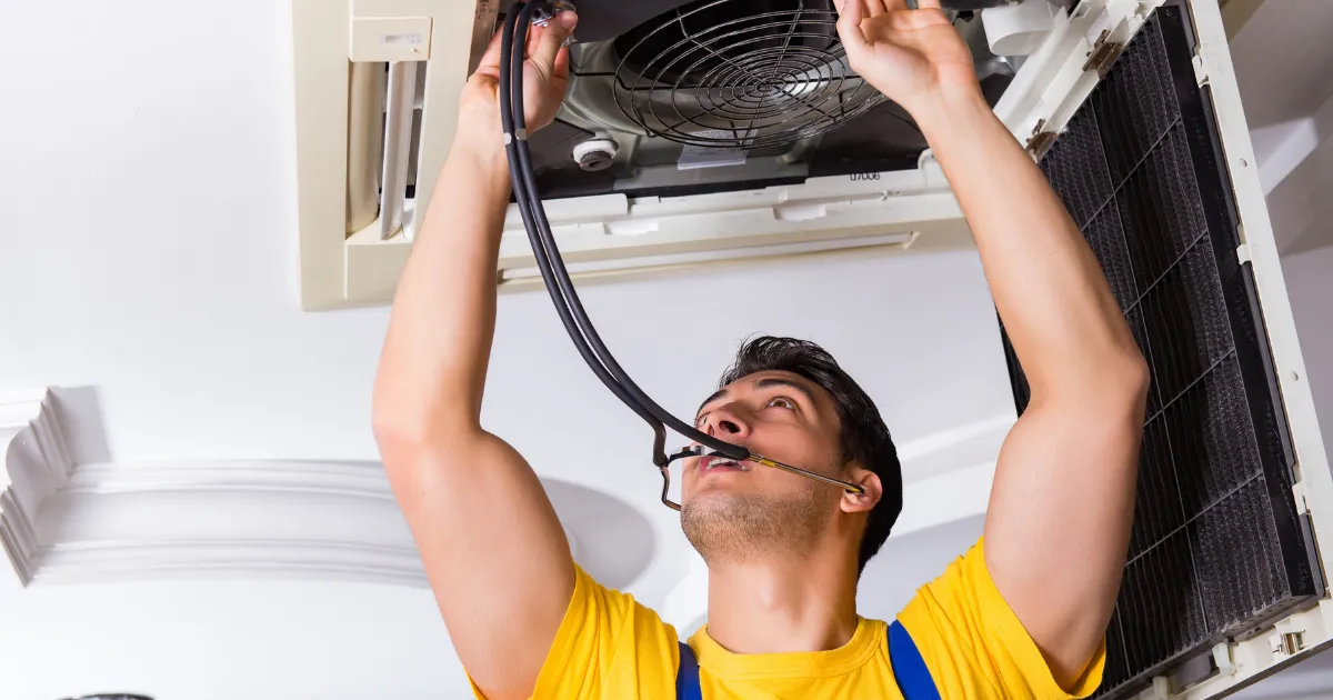 A Rapid Response team member using a stethoscope tool to detect abnormal noise or vibration in a ceiling AC unit