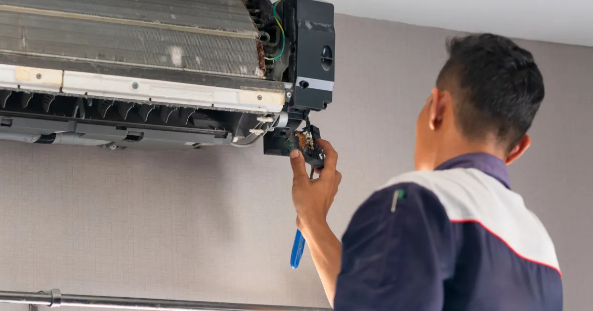 A technician  replaces a damaged electrical part inside a wall-mounted AC unit to restore proper cooling performance