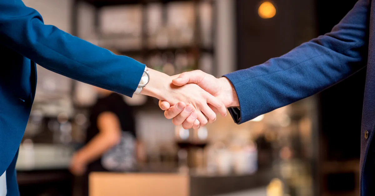 Two people in business attire shaking hands, symbolizing trust, agreement, and professional service commitment