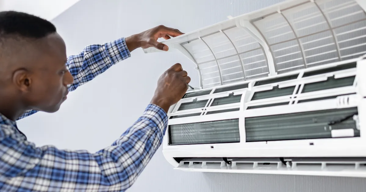 The technician is opening and inspecting the air conditioner's front panel