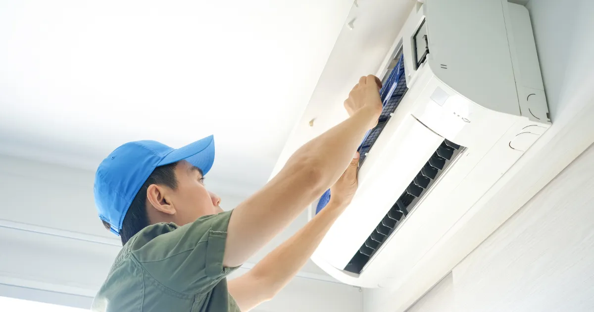 Technician in a blue cap removing and cleaning the air conditioner filter