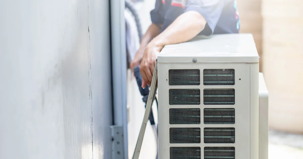 A technician is positioning an outdoor AC unit and securing the lines for proper installation and stable operation