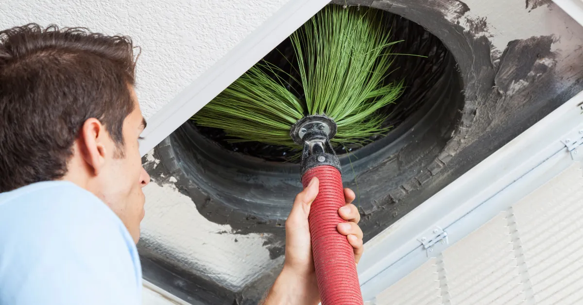 A technician is cleaning air ducts using a rotating brush tool