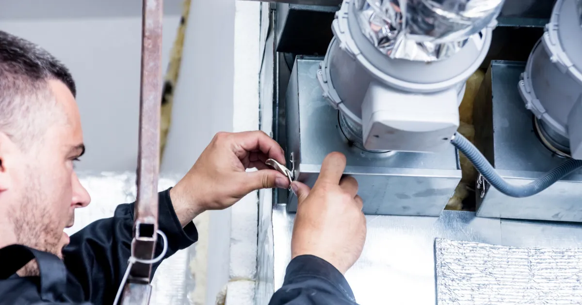 A technician is closing the air filter door on an HVAC ventilation unit