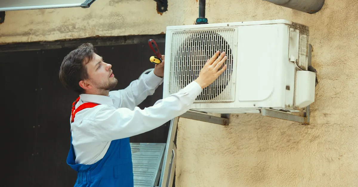 Rapid Response crew member inspecting an outdoor AC condenser unit on the side of a building