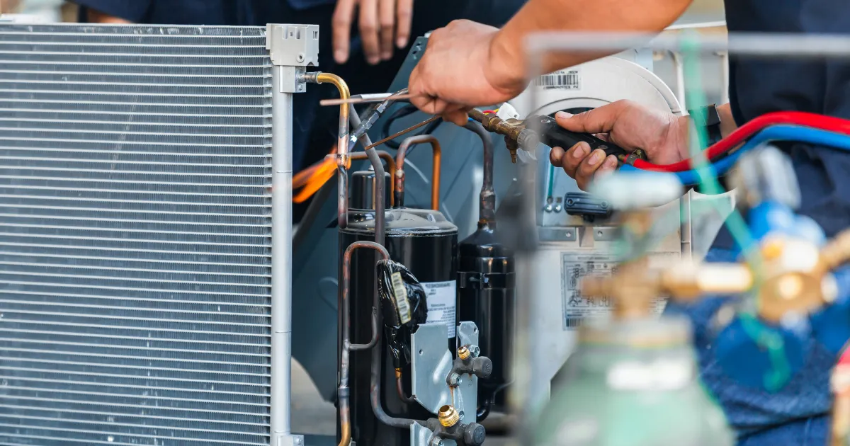 HVAC condenser unit repair with brazing torch and refrigerant lines being serviced